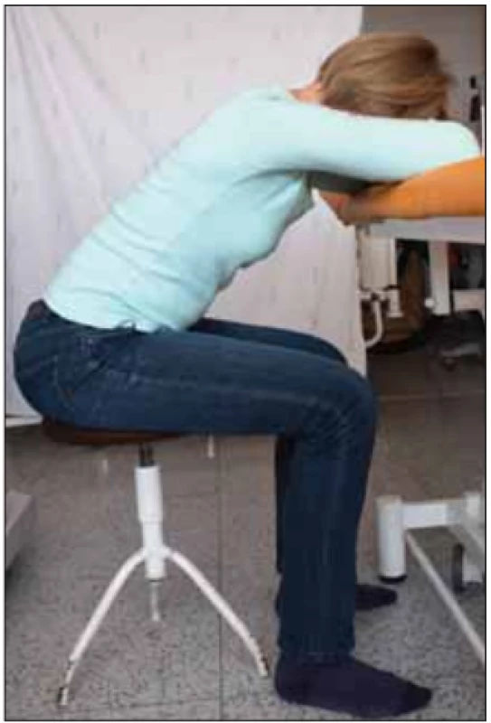 Úlevová poloha vsedě na židli s oporou horních končetin o stůl pro vytvoření
punctum fixum pomocných dechových
svalů na pletencích ramen a  k  snazšímu
rozvíjení hrudníku během dechových pohybů. Fotografi e byla pořízená s informovaným souhlasem pacientky.<br>
Fig. 4. Breath relief sitting position on
a  chair, with upper limbs supported by
a table, which creates a punctum fi xum
for accessory respiratory muscles on the
shoulder girdle. This posture facilitates
excursions of thorax movement while
breathing. The picture was taken with informed consent from the patient.